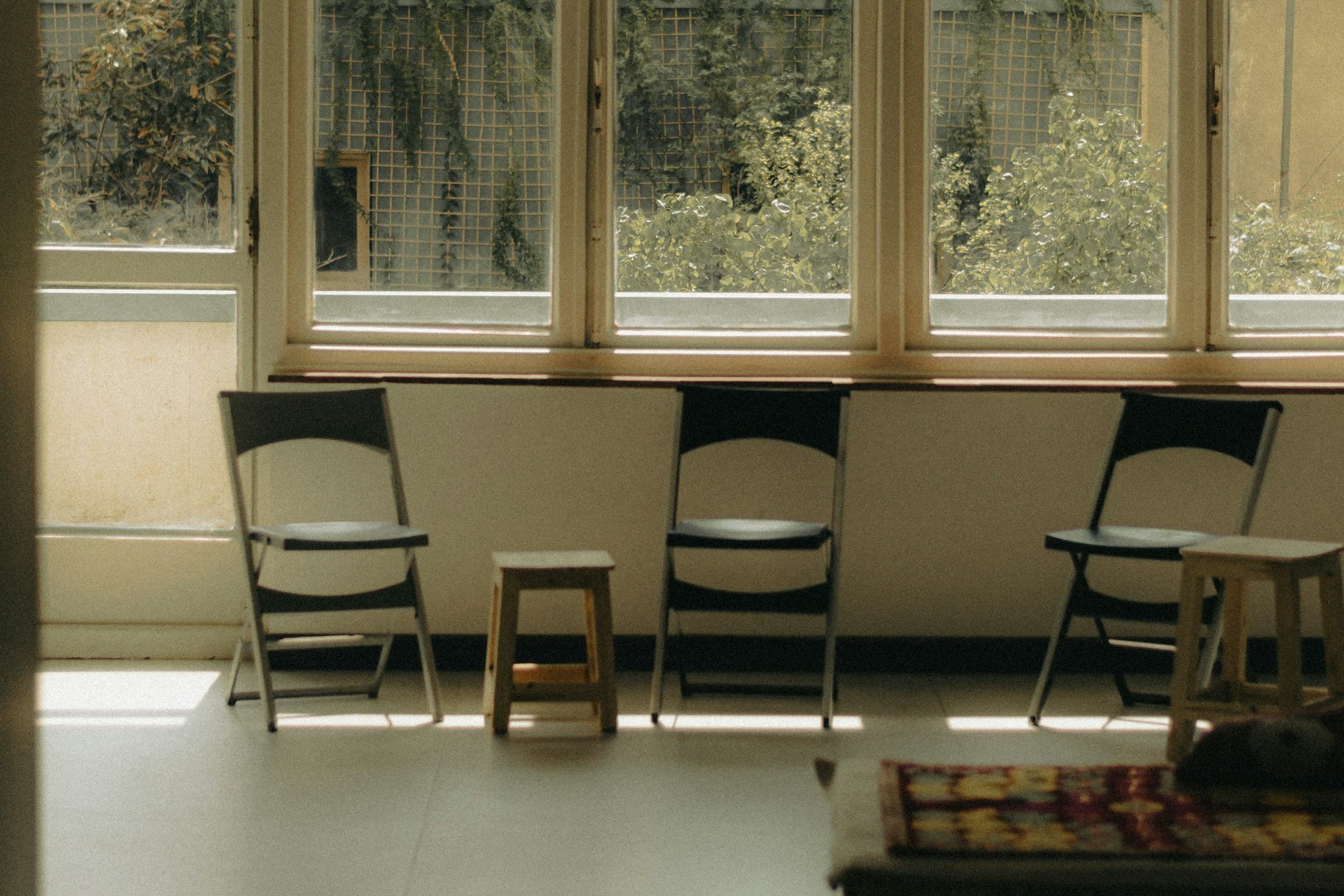 Empty chairs at a sunlit window in a quiet waiting area.